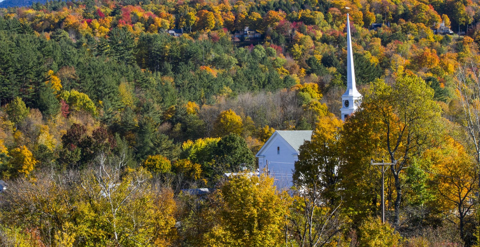 Iglesia de madera blanca entre árboles de otoño